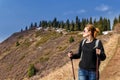 Young girl with trekking sticks walks in mountains Royalty Free Stock Photo