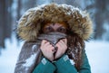 Young girl tries to keep warm in the winter forest and hide in warm clothes like owl. Winter nature. Portrait. Selective focus Royalty Free Stock Photo