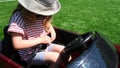 Young girl unbuckles seatbelt sitting in small toy car