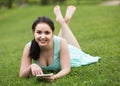 Young girl using digital tablet while lying in green spring gar Royalty Free Stock Photo