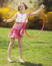 Young girl using hula hoop on arm in a park