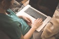 Young girl using laptop sitting on sofa with warm plaid indoors. Hands on keyboard, black screen