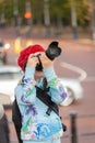 Young girl using a large digital camera in an urban setting with a blurry background