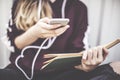 Young girl using mobile phone and reading book outside Royalty Free Stock Photo