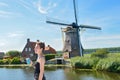 Young girl on vacation in Holland, looking at Dutch windmill from barge boat in canal, cruise trip in houseboat, Netherlands