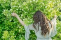 A young girl in a vintage-style dress gently embraces the shrub Philadelphus