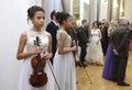 Young girl violinist standing with a violin in hand waiting for her performance during dance ball, celebration of