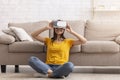 Millennial girl in virtual reality headset exploring cyberspace, playing interactive video game at home