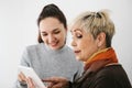 A young girl explains to an elderly woman how to use a tablet or shows some application or teaches you how to use a