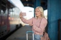 Young woman waiting for a bus on a bus station and talking on smart phone Royalty Free Stock Photo