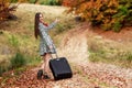 Young girl waiting on a country road with her suitcase. Royalty Free Stock Photo