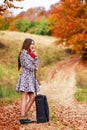 Young girl waiting on a country road with her suitcase. Royalty Free Stock Photo