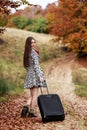 Young girl waiting on a country road with her suitcase. Royalty Free Stock Photo