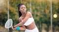 Young girl waiting to hit a ball in a tennis match. African american woman enjoying a game of tennis. Serious young Royalty Free Stock Photo