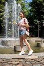 A young girl is walking in the park near the fountain and drinking lemonade Royalty Free Stock Photo