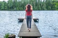 Young girl walking on the pier, back to the camera. A view of the beautiful lake. Summer mood Royalty Free Stock Photo