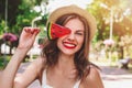 A young girl walks in the park with a lollipop in the form of watermelon. Girl in straw hat smiling in the park