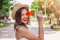 A young girl walks in the park with a lollipop in the form of watermelon. Girl in straw hat smiling in the park