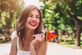 A young girl walks in the park with a lollipop in the form of watermelon. Girl in straw hat smiling in the park