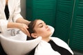 Beautiful young girl washes her head in a beauty studio. Hairdresser is washing hair for client Royalty Free Stock Photo