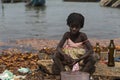 Young girl washing bottles next to the water in the port of the city of Cacheu, in Guinea Bissau.