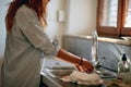 A young girl washing dishes in the kitchen. Housework, kitchen, home Royalty Free Stock Photo