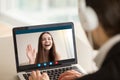 Young girl waving from laptop screen at man in headphones.