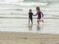 Two children, a young boy and a young girl, running through shallow waves and playing at the beach Royalty Free Stock Photo