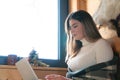 Young Girl Working On Her Laptop In A Nice Cozy Room - Sitting Next To Window Royalty Free Stock Photo