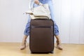 Young girl wearing jeans and high heels standing near the luggage bag and holding a handbag. Travel and relocation concept.