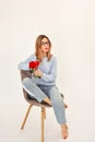 Young girl sitting on a chair holding a fresh red rose in her hand. Royalty Free Stock Photo