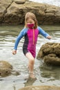 Young girl wearing a mask and colorful swimming suit having fun splashing at the beach