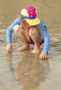 Young girl in a hat and colorful swimming suit having fun splashing at the beach