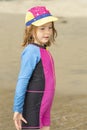 Young girl in a hat and colorful swimming suit having fun splashing at the beach Royalty Free Stock Photo