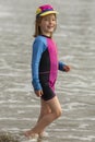Young girl in a hat and colorful swimming suit having fun splashing at the beach Royalty Free Stock Photo