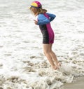 Young girl in a hat and colorful swimming suit having fun splashing at the beach Royalty Free Stock Photo