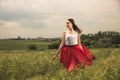 Young girl wearing a red skirt posing in a green wheat field Royalty Free Stock Photo
