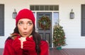 Young Girl Wearing Scarf, Red Cap and Mittens with Hot Cocoa Mug Standing on Christmas Decorated Front Porch Royalty Free Stock Photo