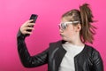 Young girl wears a black leather jacket and takes pictures with her mobile phone