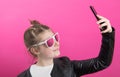 Young girl wears a black leather jacket and takes pictures with her mobile phone Royalty Free Stock Photo