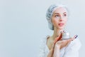 A young girl with well-groomed skin in a hat is holding a jar of cream in her hands. Place for text.