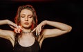 Young girl with wet, damp hair , big eyes and naked shoulders posing at dark red studio background Royalty Free Stock Photo