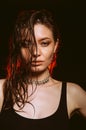 Young girl with wet, damp hair , big eyes and naked shoulders posing at dark red studio background Royalty Free Stock Photo