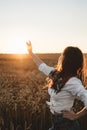 Young girl in wheat field at sunset. Curly-haired brunette white Caucasian girl watching the sunset in the field. Slow living life Royalty Free Stock Photo