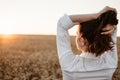 Young girl in wheat field at sunset. Curly-haired brunette white Caucasian girl watching the sunset in the field. Slow living life