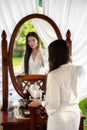 A young girl in a white coat stands in front of a mirror in the outdoor spa