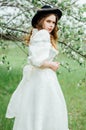 Young girl in a white dress and black hat in the in the white fl Royalty Free Stock Photo