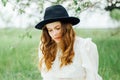 Young girl in a white dress and black hat in the in the white fl Royalty Free Stock Photo