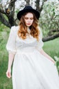 Young girl in a white dress and black hat in the in the white fl Royalty Free Stock Photo