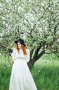 Young girl in a white dress and black hat in the in the white fl Royalty Free Stock Photo
